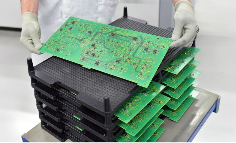 Ein Mitarbeiter von pcbwhiz an der Montagelinie hält eine fertig bestückte Leiterplatte (PCBA)